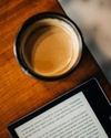 Ein Tablet und eine Tasse Kaffee auf einem Holztisch